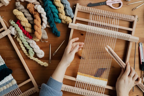Top view of artisan hands weaving on a traditional hand loom